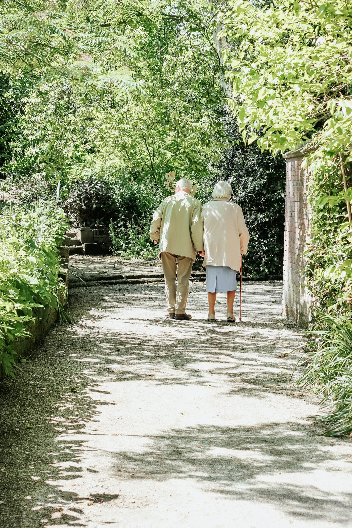 An older couple walking together along a park path